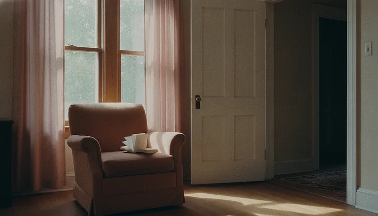 An armchair by a window in a quiet flat, with the door to the hallway standing wide open.